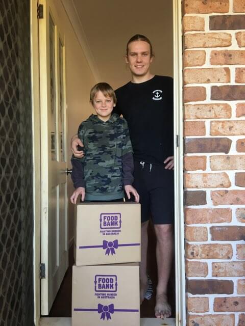 recipients smiling with their two boxes of food donation