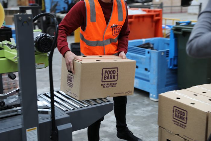 Foodbank VIC staff carrying a foodbank box of food donation