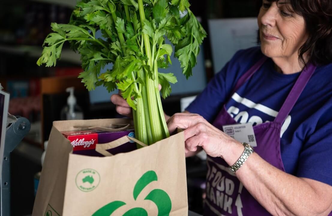 woman putting celery in a paper bag
