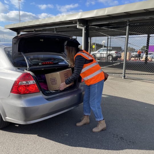 woman putting foodbank food box on the car