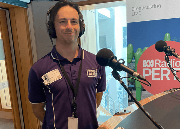 man wearing a purple foodbank shirt and headphones