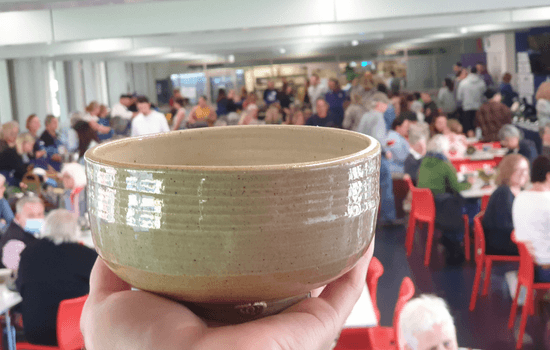 a hand holding an empty bowl to highlight the event