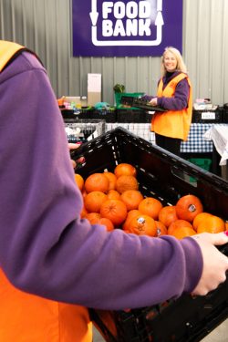 fruits in a black tray carried by a foodbank volunteer