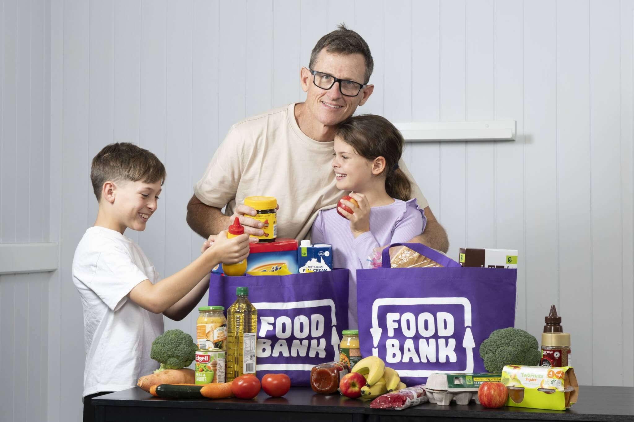 Family unpacking Foodbank Queensland grocery bags with fresh food and pantry items supporting food security