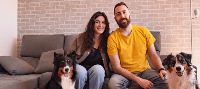 Young couple sitting on couch at home with dogs
